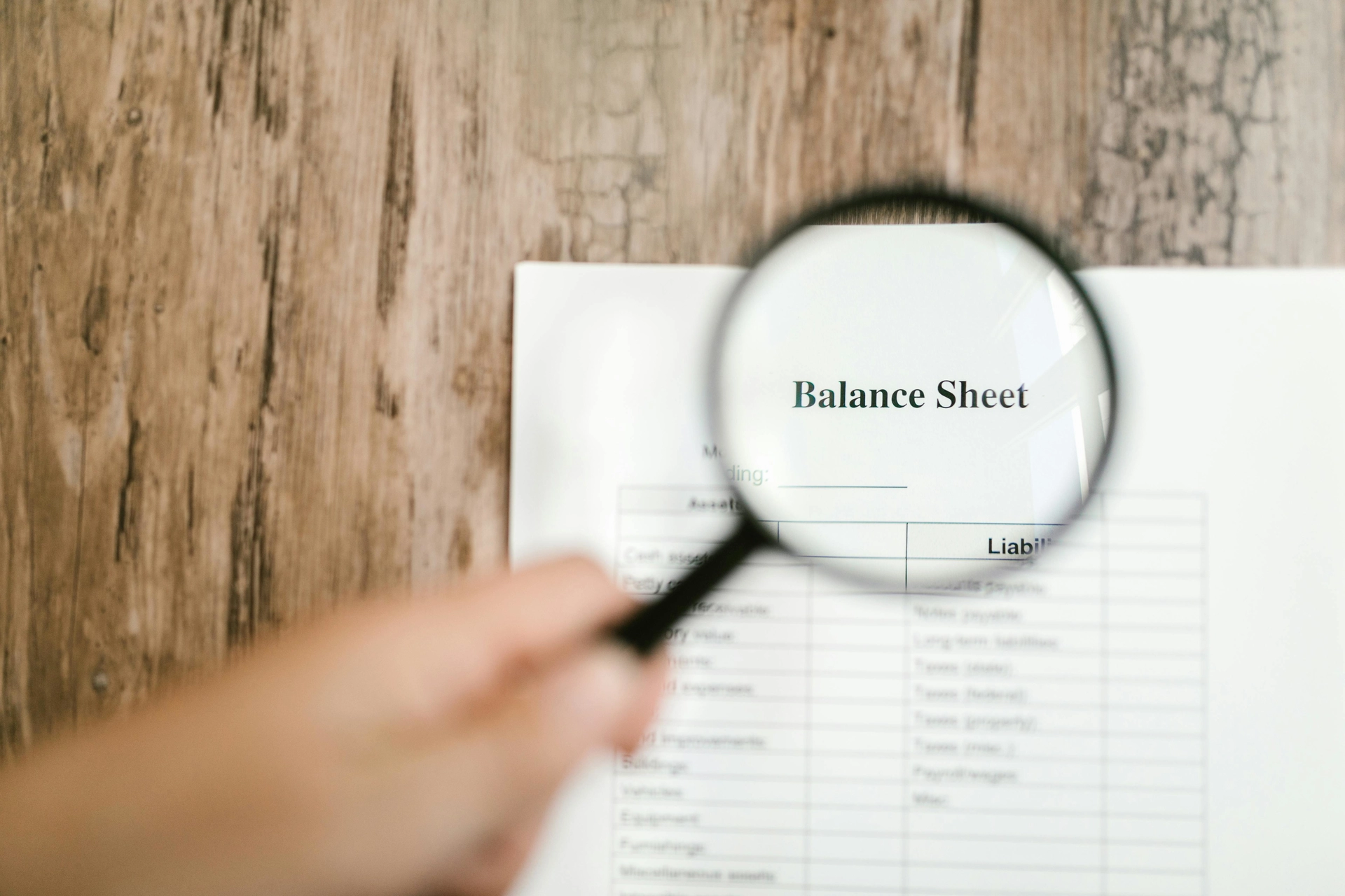 Magnifying glass over the words Balance Sheet on a piece of paper